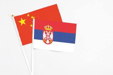 Serbia and China stick flags on white background. High quality fabric, miniature national flag. Peaceful global concept.White floor for copy space.