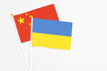 Ukraine and China stick flags on white background. High quality fabric, miniature national flag. Peaceful global concept.White floor for copy space.