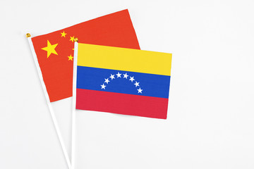 Venezuela and China stick flags on white background. High quality fabric, miniature national flag. Peaceful global concept.White floor for copy space.