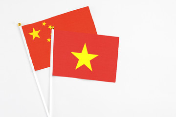 Vietnam and China stick flags on white background. High quality fabric, miniature national flag. Peaceful global concept.White floor for copy space.