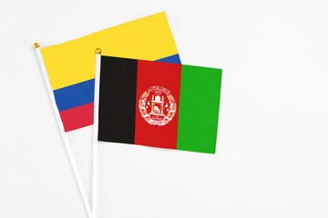 Afghanistan and Colombia stick flags on white background. High quality fabric, miniature national flag. Peaceful global concept.White floor for copy space.