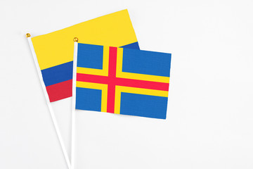 Aland Islands and Colombia stick flags on white background. High quality fabric, miniature national flag. Peaceful global concept.White floor for copy space.