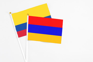 Armenia and Colombia stick flags on white background. High quality fabric, miniature national flag. Peaceful global concept.White floor for copy space.