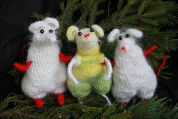 Three knitted mouse toys with fir branches
