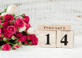 Bouquet of red roses and data 14 of February on wooden calendar on the white background. Happy Valentines Day, february 14 , copy space. Greeting card. Top view, flat lay. Love concept