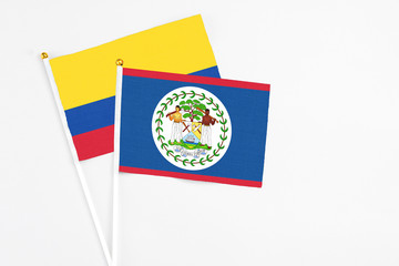 Belize and Colombia stick flags on white background. High quality fabric, miniature national flag. Peaceful global concept.White floor for copy space.