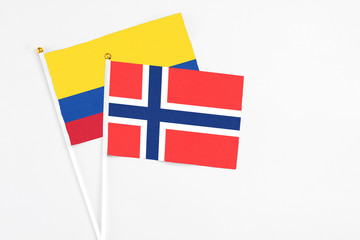 Bouvet Islands and Colombia stick flags on white background. High quality fabric, miniature national flag. Peaceful global concept.White floor for copy space.