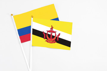 Brunei and Colombia stick flags on white background. High quality fabric, miniature national flag. Peaceful global concept.White floor for copy space.