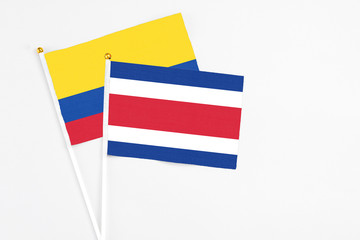 Costa Rica and Colombia stick flags on white background. High quality fabric, miniature national flag. Peaceful global concept.White floor for copy space.