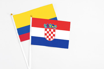 Croatia and Colombia stick flags on white background. High quality fabric, miniature national flag. Peaceful global concept.White floor for copy space.