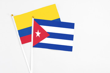 Cuba and Colombia stick flags on white background. High quality fabric, miniature national flag. Peaceful global concept.White floor for copy space.