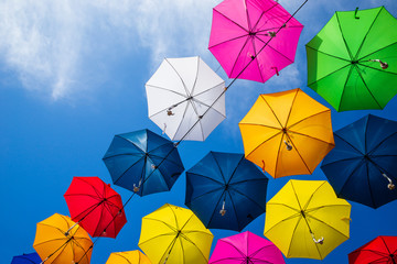 Beautiful group of colorful umbrellas hanging above the street against blue sky on a sunny day