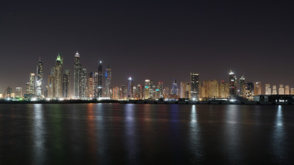 Fototapeta na wymiar Dubai skyline at night with lights reflections on the Gulf 