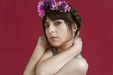 Young woman dancing with white dress and flowers in her hair. Red background.