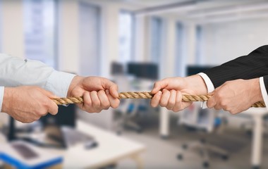 Business people pulling rope in opposite directions at office