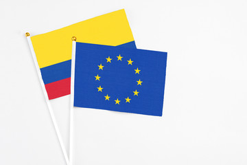 European Union and Colombia stick flags on white background. High quality fabric, miniature national flag. Peaceful global concept.White floor for copy space.