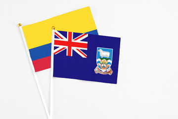 Fototapeta premium Falkland Islands and Colombia stick flags on white background. High quality fabric, miniature national flag. Peaceful global concept.White floor for copy space.