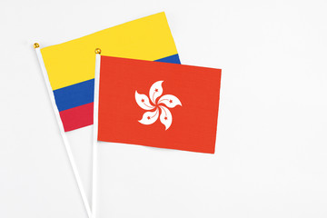 Hong Kong and Colombia stick flags on white background. High quality fabric, miniature national flag. Peaceful global concept.White floor for copy space.