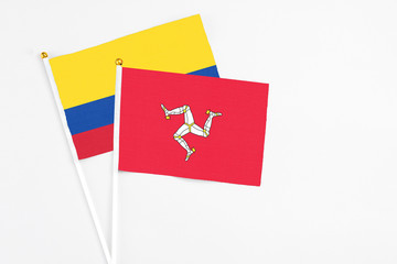 Isle Of Man and Colombia stick flags on white background. High quality fabric, miniature national flag. Peaceful global concept.White floor for copy space.