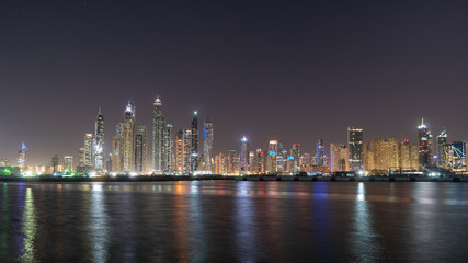 Fototapeta na wymiar JBR skyline at night full of colorful lights reflections on the water