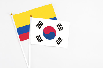 South Korea and Colombia stick flags on white background. High quality fabric, miniature national flag. Peaceful global concept.White floor for copy space.