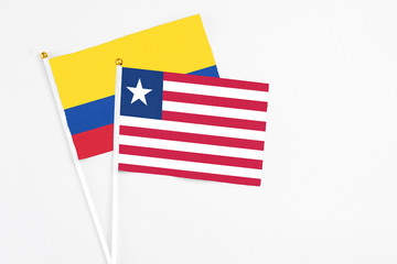 Liberia and Colombia stick flags on white background. High quality fabric, miniature national flag. Peaceful global concept.White floor for copy space.