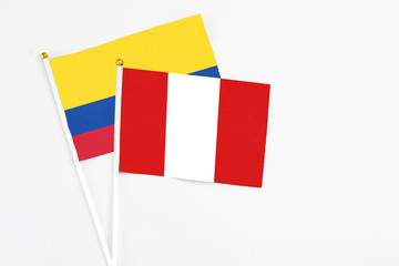 Peru and Colombia stick flags on white background. High quality fabric, miniature national flag. Peaceful global concept.White floor for copy space.