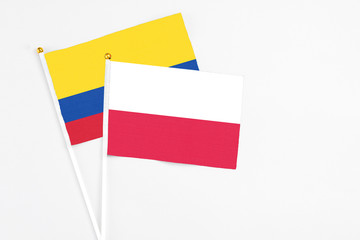 Poland and Colombia stick flags on white background. High quality fabric, miniature national flag. Peaceful global concept.White floor for copy space.