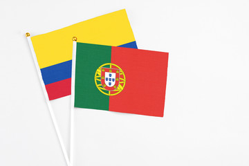 Portugal and Colombia stick flags on white background. High quality fabric, miniature national flag. Peaceful global concept.White floor for copy space.