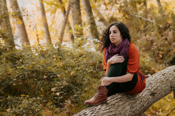 Young woman, dressed in casual clothes, with relaxed attitude, in a forest with autumn colors.