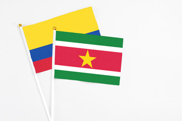 Suriname and Colombia stick flags on white background. High quality fabric, miniature national flag. Peaceful global concept.White floor for copy space.