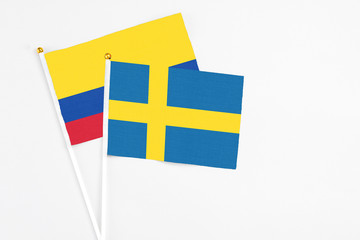 Sweden and Colombia stick flags on white background. High quality fabric, miniature national flag. Peaceful global concept.White floor for copy space.