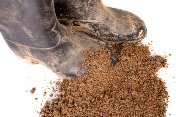 dirty rubber boots on a white background. soil macro on white.
