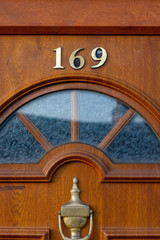 House number 169 on a wooden front door with glass