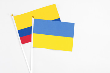 Ukraine and Colombia stick flags on white background. High quality fabric, miniature national flag. Peaceful global concept.White floor for copy space.