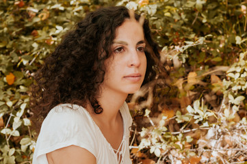 Young woman, dressed in casual clothes, with relaxed attitude, in a forest with autumn colors.