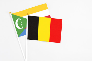 Belgium and Comoros stick flags on white background. High quality fabric, miniature national flag. Peaceful global concept.White floor for copy space.