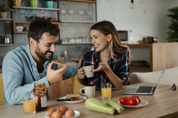 Young cheerful couple having fun during breakfast time in the kitchen