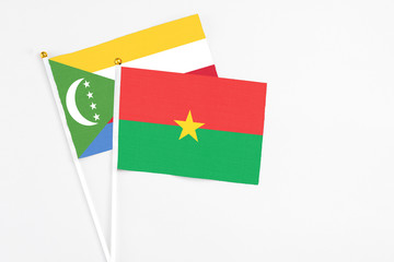 Burkina Faso and Comoros stick flags on white background. High quality fabric, miniature national flag. Peaceful global concept.White floor for copy space.