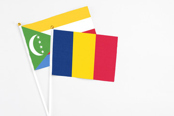 Chad and Comoros stick flags on white background. High quality fabric, miniature national flag. Peaceful global concept.White floor for copy space.