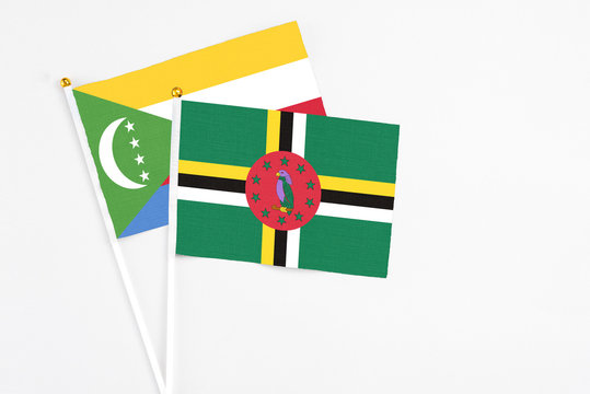 Dominica and Comoros stick flags on white background. High quality fabric, miniature national flag. Peaceful global concept.White floor for copy space.