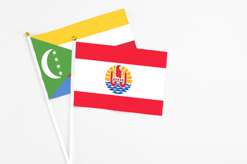 French Polynesia and Comoros stick flags on white background. High quality fabric, miniature national flag. Peaceful global concept.White floor for copy space.