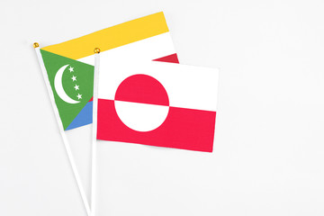 Greenland and Comoros stick flags on white background. High quality fabric, miniature national flag. Peaceful global concept.White floor for copy space.