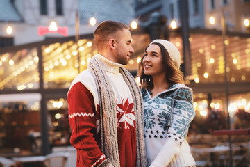 Fototapeta premium Lovely couple feels happy on the Christmas market, surrounded with warm lights.