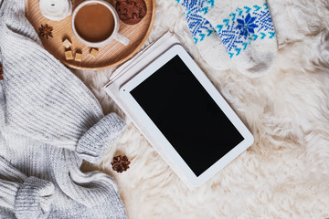 Tablet with blank screen, warm sweater and a cup of coffee on the fur