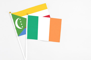 Ireland and Comoros stick flags on white background. High quality fabric, miniature national flag. Peaceful global concept.White floor for copy space.