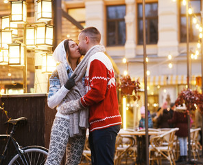 Lovely couple are kissing on the street while have a date on Christmas day.