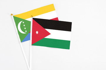 Jordan and Comoros stick flags on white background. High quality fabric, miniature national flag. Peaceful global concept.White floor for copy space.