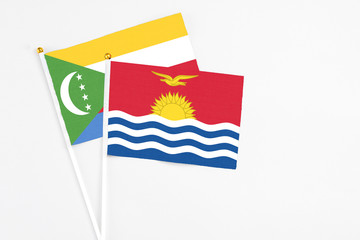 Kiribati and Comoros stick flags on white background. High quality fabric, miniature national flag. Peaceful global concept.White floor for copy space.