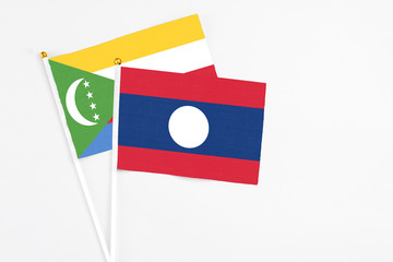 Laos and Comoros stick flags on white background. High quality fabric, miniature national flag. Peaceful global concept.White floor for copy space.